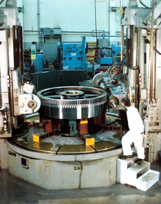 A large bull gear being machined with a worker for scale at Gear Force Machine.