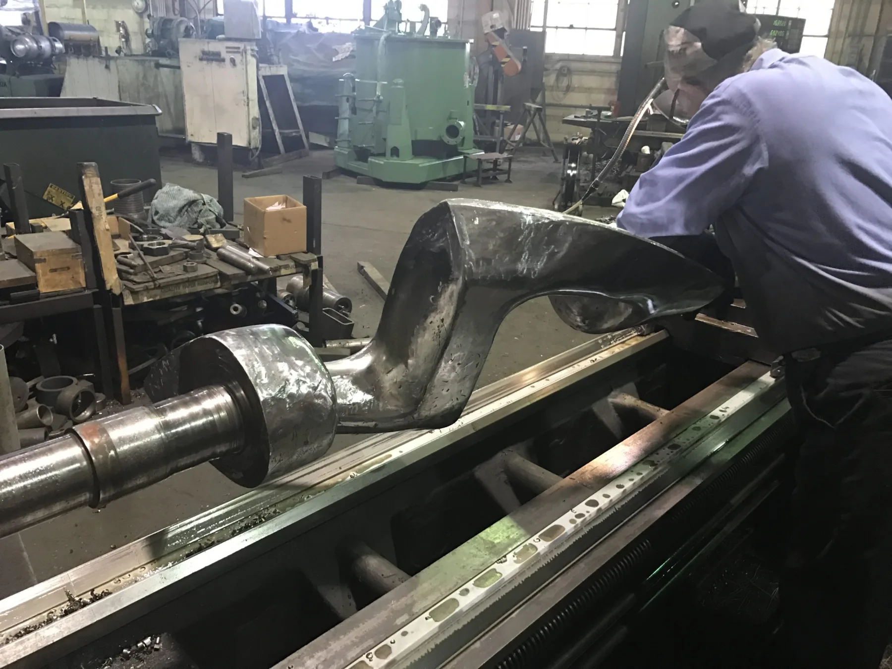 A machinist turning a large Sigma mixer blade on the lathe at Gear Force Machine.