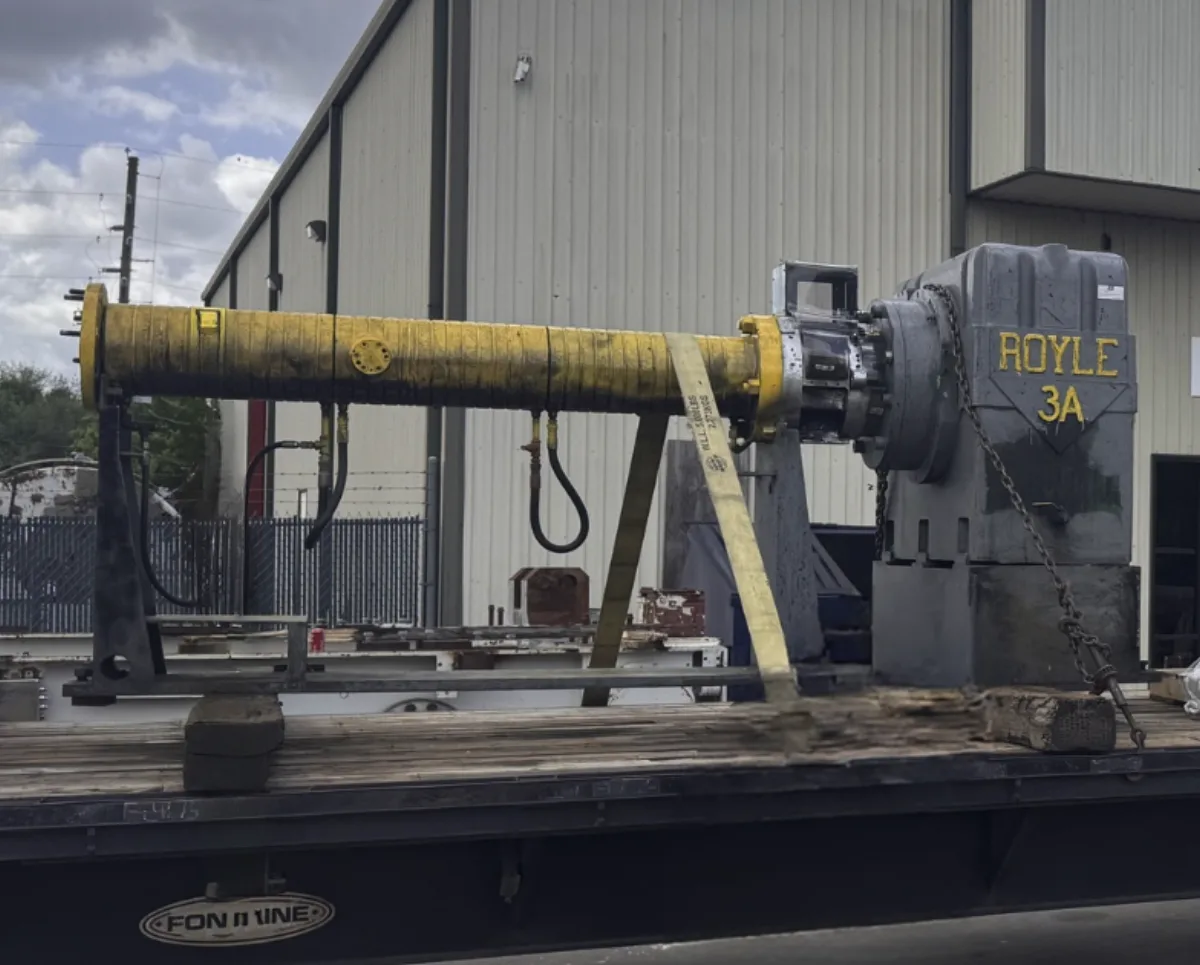 A worn Royle 3A extruder gearbox and barrel with corroded yellow paint, staged on a flatbed before rebuild.