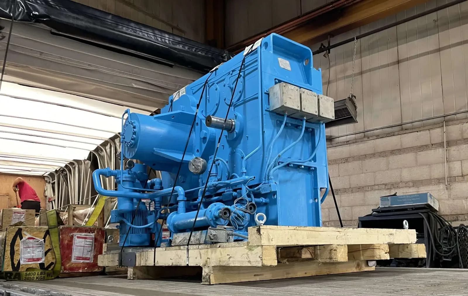 A large blue Farrel/Pomini industrial gearbox staged on wooden dunnage in the Gear Force Machine shop, ready for shipment after rebuild.