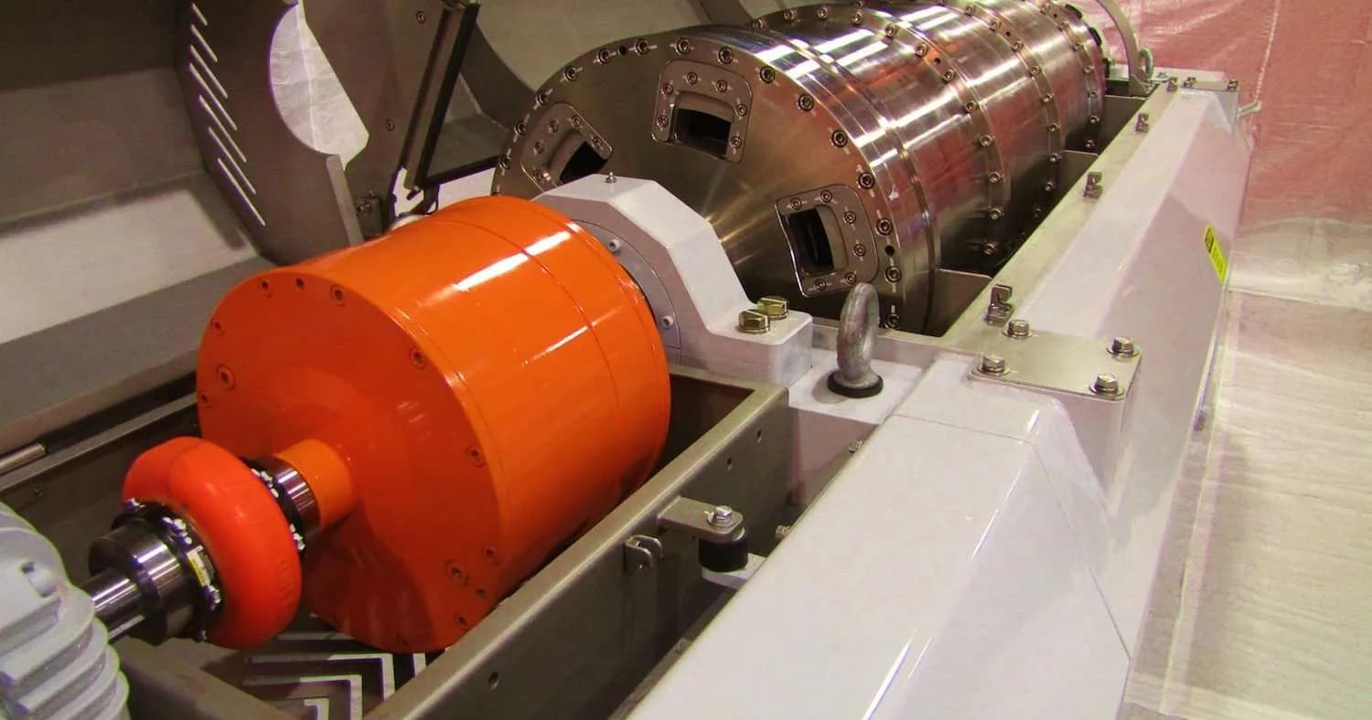 A rebuilt decanter centrifuge rotating assembly with a bright orange backdrive on a white base at Gear Force Machine.