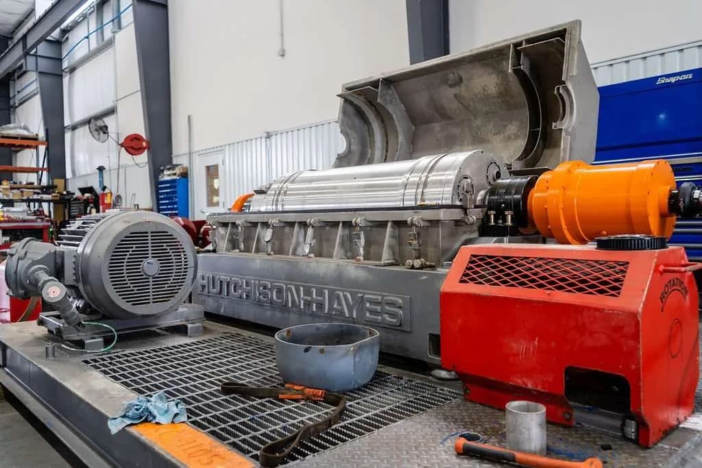 A Hutchison-Hayes decanter centrifuge open on the test stand with an orange backdrive gearbox at Gear Force Machine.