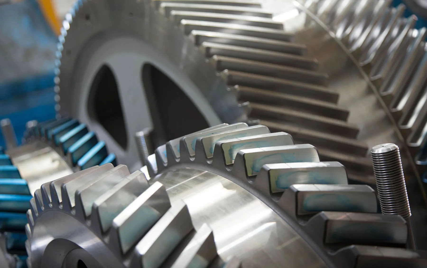 A tight macro of meshing helical gears with blue machining marks at Gear Force Machine.