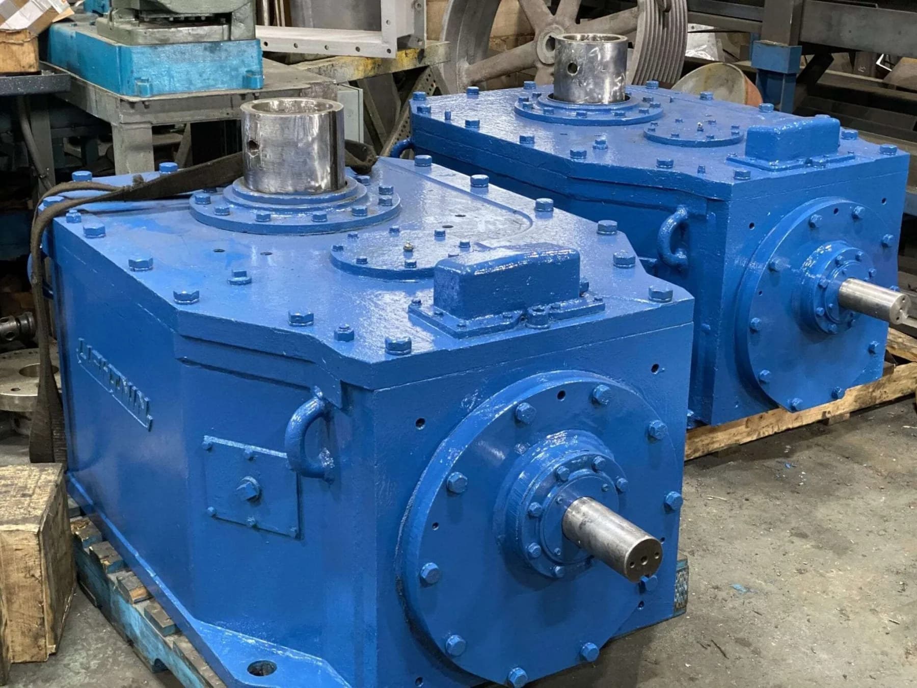 Two freshly painted blue rebuilt industrial gearboxes staged on pallets at the Gear Force Machine shop.