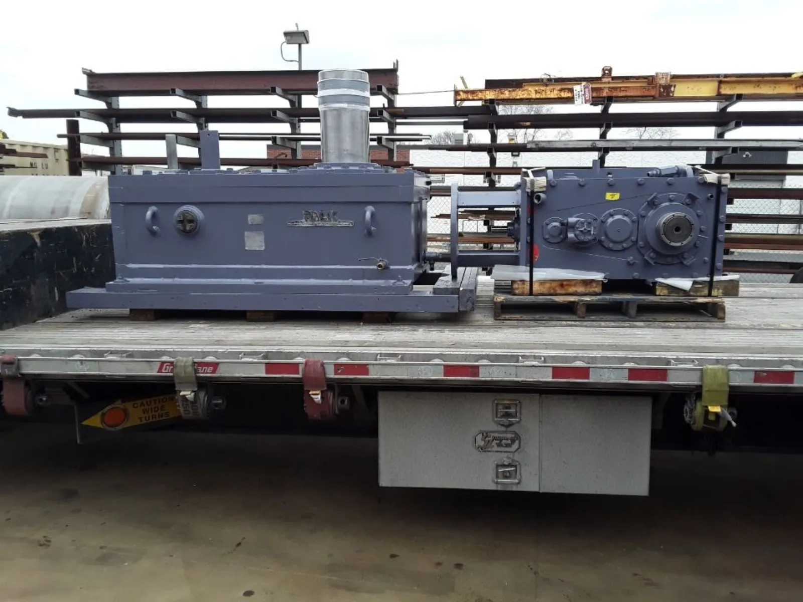Two rebuilt gearboxes chained to a flatbed truck at a refinery, staged for return to an oil and gas facility by Gear Force Machine.