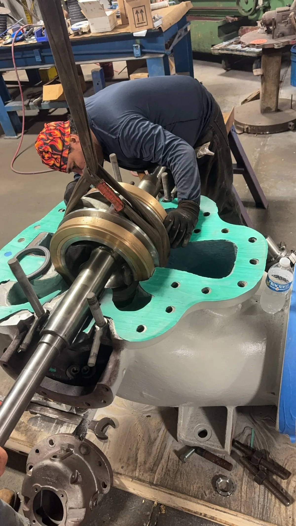 A technician fitting the bronze bearing housing and shaft assembly into an Ingersoll Rand pump casing during rebuild.