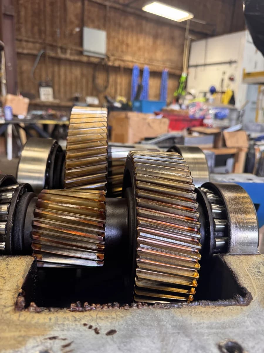 Close-up of a freshly machined gear cluster and countershaft assembly with bright, oil-sheened teeth.