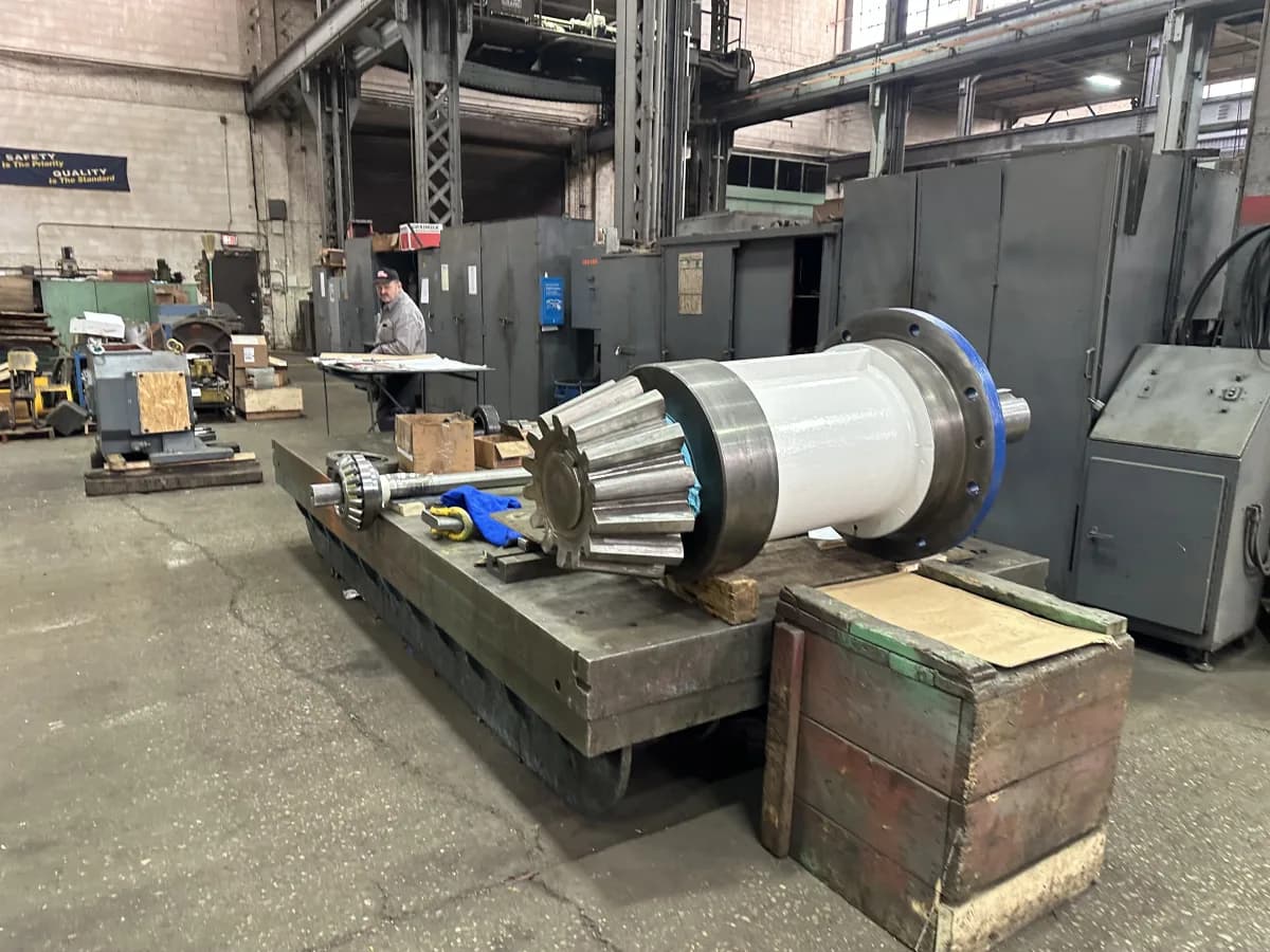 A large custom bevel gear and shaft assembly staged on a shop cart during fabrication.
